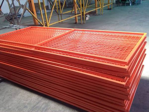 Several orange color Canadian temporary fencing panels in the warehouse.
