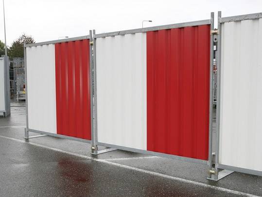 White and red hoarding panel system with galvanized frame and metal feet on highway.