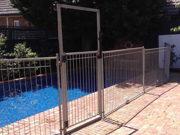 Temporary pool fencing with self-closing gate are protecting swimming pools.