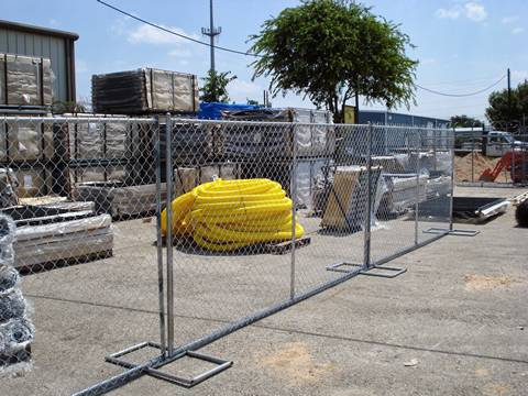 Several plastic pipes and equipment are in the area enclosed by temporary chain link fences.